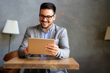 Gülümseyen başarılı iş adamı, resmi iş süitinde dijital tablet üzerinde çalışan girişimci
