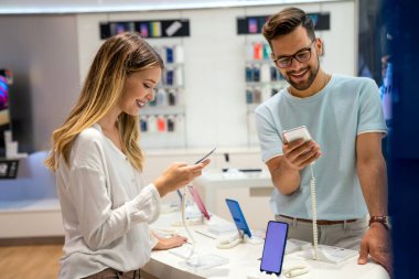 Mobil dükkanından yeni akıllı telefon alan mutlu gençler. Teknoloji Mutluluğu Cihaz Alışverişi