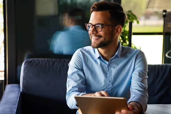 Gülümseyen başarılı iş adamı, resmi iş süitinde dijital tablet üzerinde çalışan girişimci