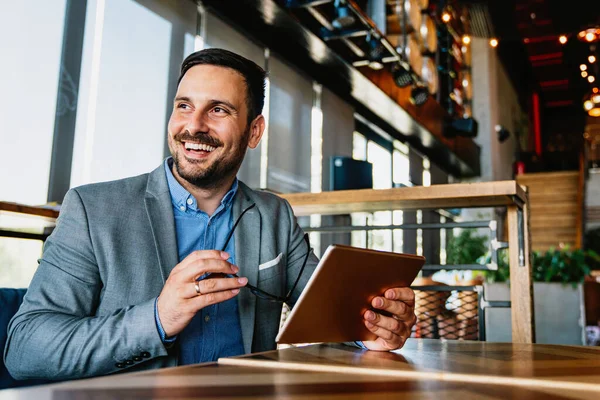 Dijital cihazlı başarılı bir iş adamının portresi. Şirket ofisinde çalışıyor.