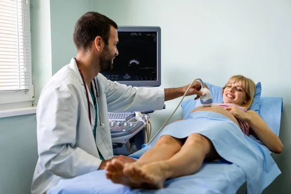 Doğum uzmanı hastanede ultrasonik taramayla hamile kadının karnını muayene ediyor. Sağlık, jinekolog, annelik konsepti..