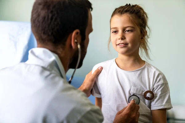 若い医者は入院中の聴診器で少女を調べる 小児科の概念 — ストック写真