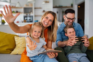 Dijital cihaz teknolojisi aile çevrimiçi eğitim kavramı. Evde dijital cihazları olan mutlu genç bir aile..