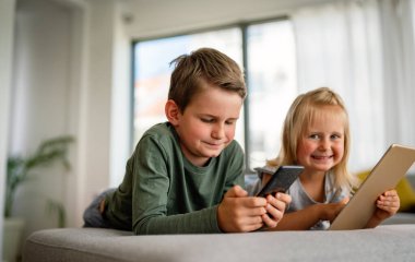 Küçük kız ve oğlan video izliyor ya da dijital cihaz tabletlerinde oyun oynuyorlar, akıllı telefon. Çocuklar dijital bağımlılık kavramı.