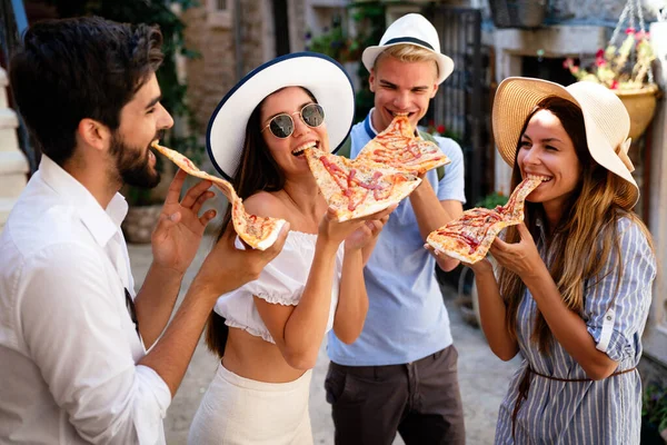 Happy group of friends eating pizza while traveling on vacation