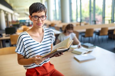 Öğrenciler kütüphanede okuyor. Gençler birlikte zaman geçirip birlikte öğreniyor..