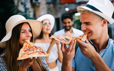 Arkadaşlar dışarıda eğleniyor, yaz tatilinde pizza yiyorlar.
