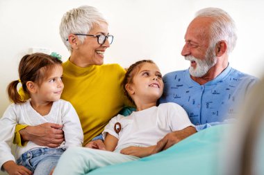 Mutlu büyükanne ve büyükbabalar evde torunlarıyla eğleniyor.