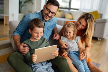 Happy young family having fun time at home. Parents with children using digital device. Education parenting happiness concept.