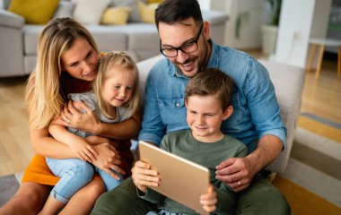 Happy young family having fun time at home. Parents with children using digital device. Education parenting happiness concept.