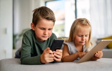 Küçük kız ve oğlan video izliyor ya da dijital cihaz tabletlerinde oyun oynuyorlar, akıllı telefon. Çocuklar dijital bağımlılık kavramı.