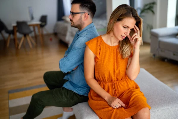 Sad pensive couple thinking of relationships problems sitting on sofa, conflicts in marriage, upset couple after fight dispute, making decision of breaking up get divorced