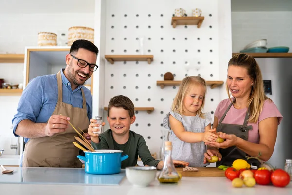 Happy young family preparing healthy food together in kitchen. People happiness cooking concept