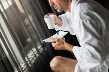 Yakışıklı, kaslı, genç adam sabah kahvesini evde içiyor.