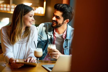 Kafede oturup tabletle eğlenen genç ve güzel bir çift. Tatilde kafede öğrenciler. Aşk, romantizm, randevu, yaşam tarzı, eğitim