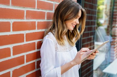 Gençlik ve teknoloji. Dışarıda tablet bilgisayar kullanan çekici genç ve mutlu bir iş kadını..
