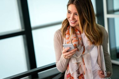 Genç ve güzel bir kızın açık hava portresi, gülen ve cep telefonu kullanan bir öğrenci.