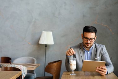 Gülümseyen başarılı iş adamı, resmi iş süitinde dijital tablet üzerinde çalışan girişimci