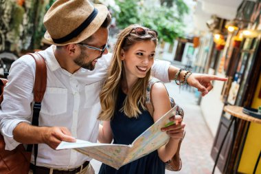 Happy young couple of travelers with map having fun on vacation together. People happiness concept clipart
