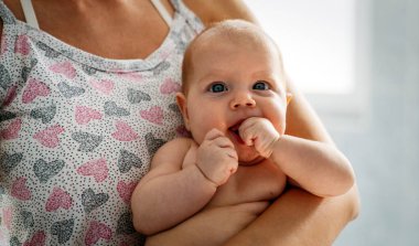 Genç ve mutlu anne yeni doğmuş bebeğine gülümsüyor. Aile, çocuk, insan kavramı