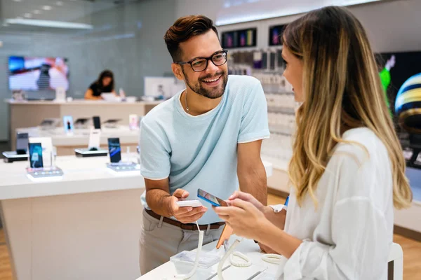 Happy young people buying new smartphone in mobile shop. Technology happiness device shopping concept