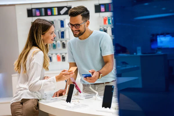 Shopping a new digital device. Happy couple buying a mobile phone in store.