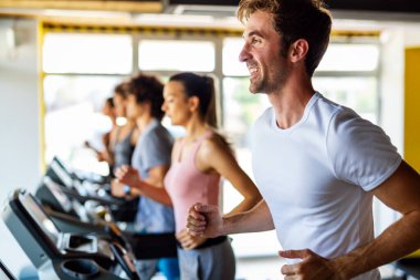 Bir grup fit genç, sağlık kulübünde koşu bandında koşan arkadaşlar. İnsanlar spor konsepti