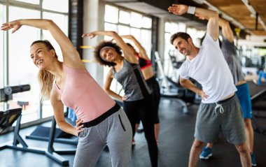 Spor salonunda spor yapan formda insanlardan oluşan bir grup. Spor salonunda birlikte egzersiz yapan çok ırklı arkadaşlar..