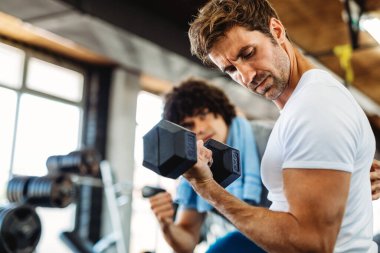 Sağlıklı kalmak için spor salonunda kişisel antrenörle çalışan zinde bir genç. Spor, insanların kavramı