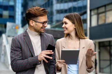 Başarılı genç iş adamları, tasarımcılar konuşuyor, modern iş binası önünde birlikte çalışıyorlar.