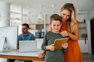 Uzaktan öğrenme, online eğitim, ev işi okulu konsepti. Evde dijital cihazları olan mutlu bir aile.