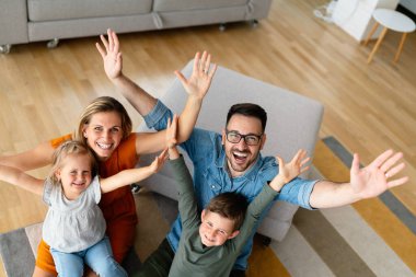 Mutlu genç aile evde eğleniyor. Ebeveynler çocuklarıyla gülümseme oyunu oynuyorlar..