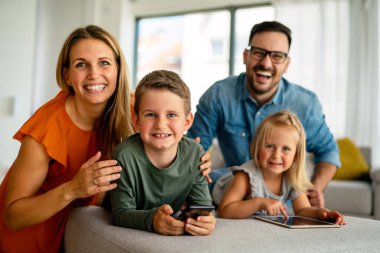 Happy young family having fun time at home. Parents with children using digital device. Education parenting happiness concept.