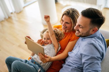 Mutlu aile evde vakit geçiriyor ve dijital cihazları birlikte kullanıyorlar. Teknoloji insanları eğlenceli konsept.