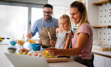 Genç ve mutlu bir aile mutfakta birlikte sağlıklı yemekler hazırlıyor. İnsanlar mutluluk aşçılık konsepti