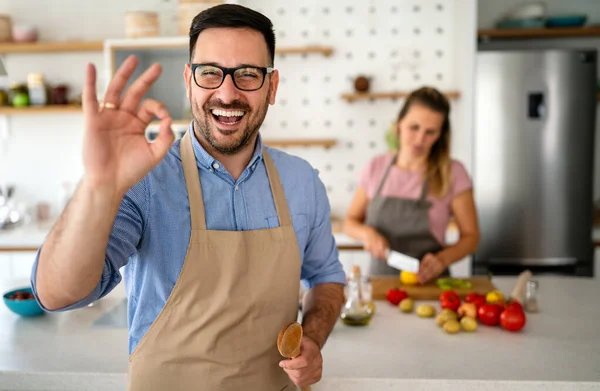 英俊潇洒的年轻快乐男子在家做饭在厨房做饭的画像 — 图库照片
