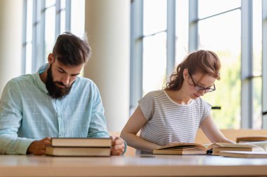 Öğrenciler kütüphanede okuyor. Gençler birlikte zaman geçirip birlikte öğreniyor..