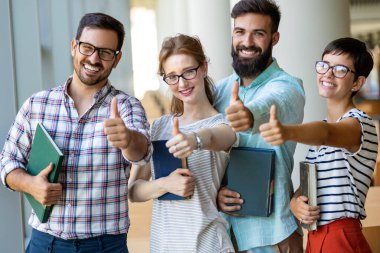 Bir üniversite kütüphanesinde birlikte çalışan mutlu bir öğrenci grubu. Eğitim insanları takım çalışması kavramı.