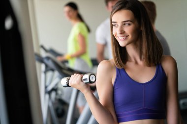 Spor salonunda dambıllarla çalışan çekici bir kadın..