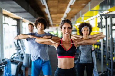 Çok ırklı bir grup insan spor salonunda antrenman yapıyor. Antrenör ve sportif fit insanlar bir fitness sınıfında egzersiz yapıyor