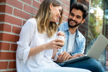 Mutlu genç iş adamları dışarıda dijital cihazlar kullanarak sohbet ediyorlar. İnsanlar teknoloji iş kavramı.