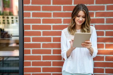 Güzel genç bayan dijital tablet kullanıyor ve gülümsüyor. İnsanlar teknoloji iş kavramı.