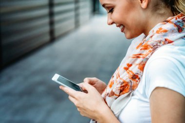 Güzel genç bir iş, dışarıda cep telefonu kullanan öğrenci bir kadın. İnsanlar iletişim teknolojisi kavramı.