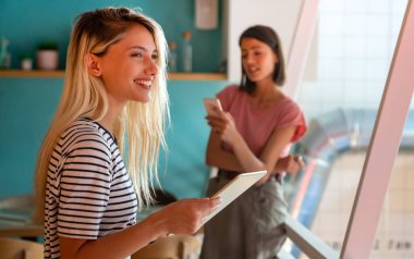 Ofiste tabletle çalışan genç ve mutlu kadınlar. İnsanlar dijital aygıt işletme eğitimi kavramı