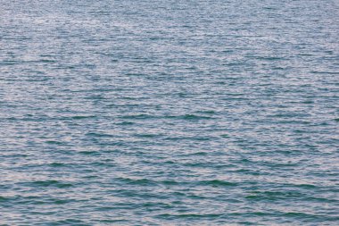 Blue turquoise transparent water surface of a sea with small waves. Texture
