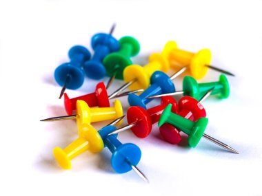 Closeup of Many Colored Thumbtacks on White. Object