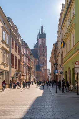 Krakow, Poland - 14 March, 2022: Tourists walking through Florianska street with St. Mary's Basilica church in background