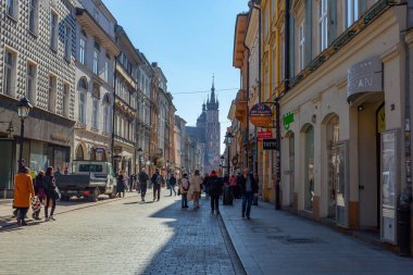 Krakow, Poland - 14 March, 2022: Tourists walking through Florianska street with St. Mary's Basilica church in background