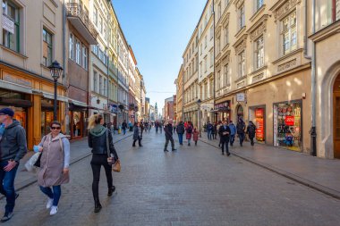 Krakow, Poland - 14 March, 2022: Tourists walking through Florianska street with St. Mary's Basilica church in background