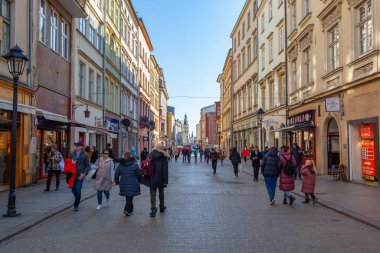 Krakow, Poland - 14 March, 2022: Tourists walking through Florianska street with St. Mary's Basilica church in background